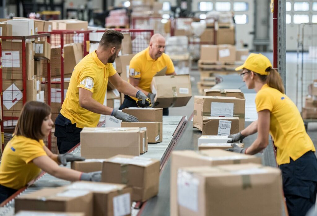 Operai lavorano su una linea di produzione per l'imballaggio di prodotti destinati a spedizioni nazionali ed internazionali